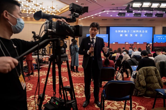 Un giornalista televisivo lavora in vista di una conferenza stampa al media center per la quarta sessione della 13a Conferenza consultiva politica del popolo cinese (PCC) a Pechino il 3 marzo 2021. (Immagine: foto di NICOLAS ASFOURI / AFP tramite Getty Images)